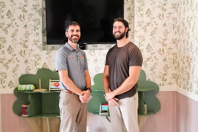 Dr. Grayson Fox and Dr. Logan Swaim talk beside the spinal anatomy chart at the clinic.