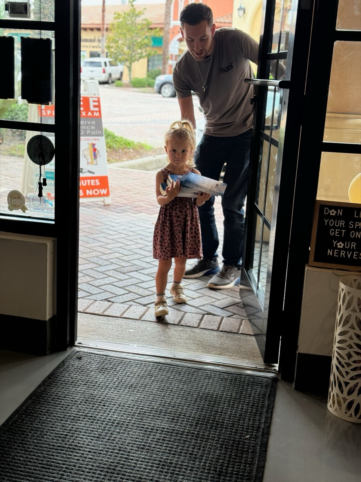 A dad and his daughter walk hand-in-hand into the clinic.