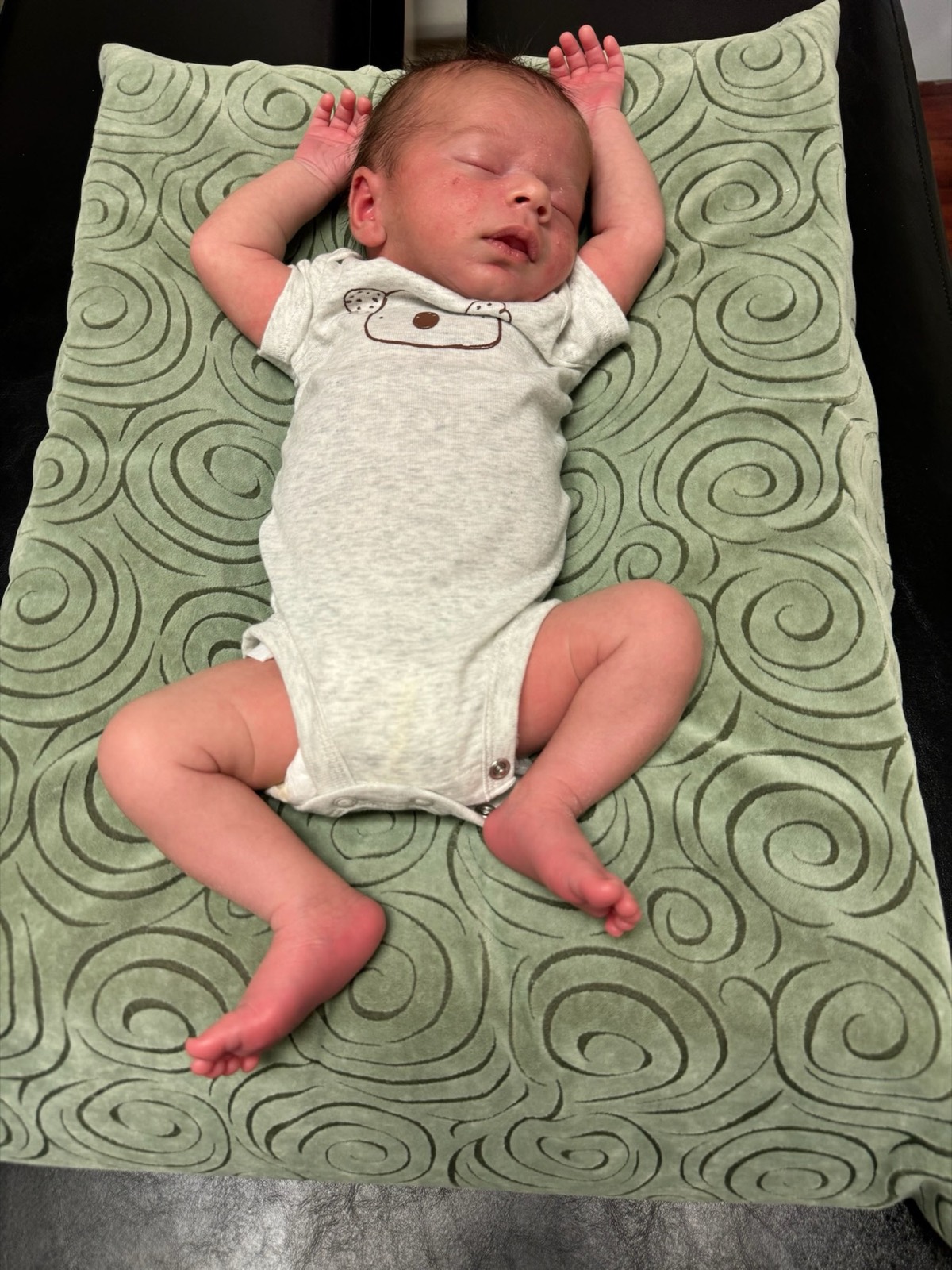 A newborn sleeps soundly on a soft pillow on the adjustment table.