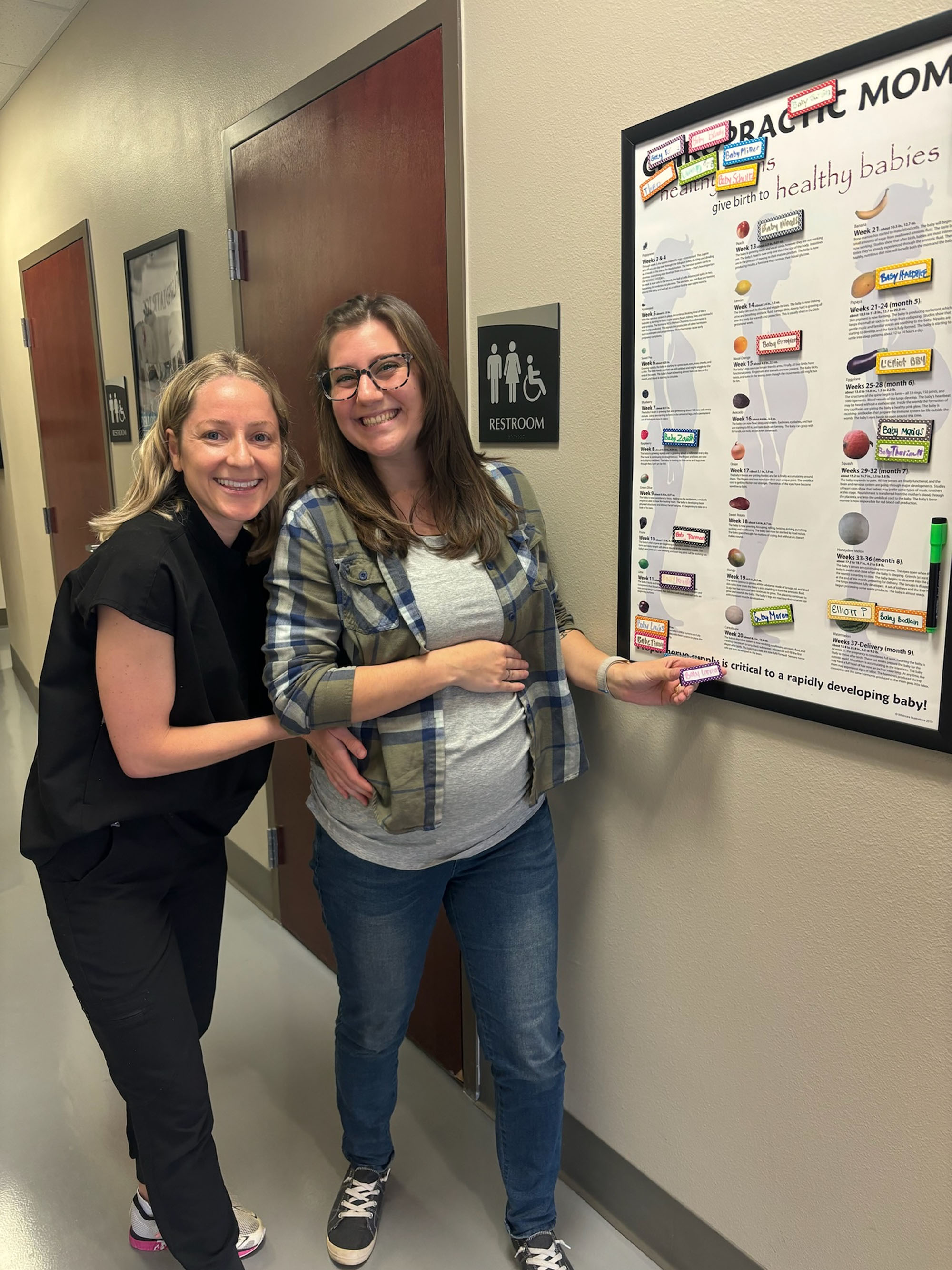 A pregnant patient reviewing the Chiropractic Moms wall.