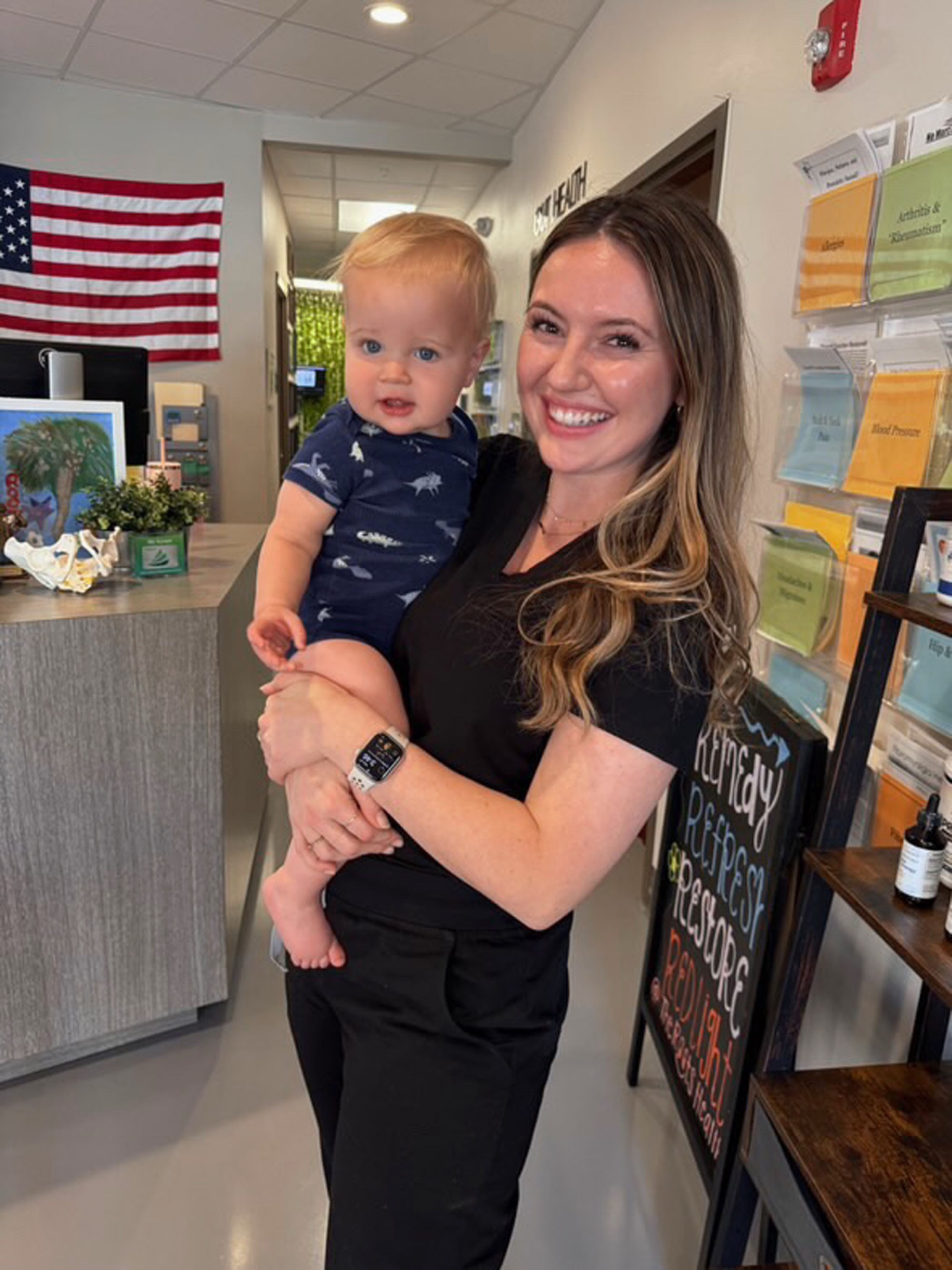 Carly holds a curious toddler at the Little Roots reception lobby.
